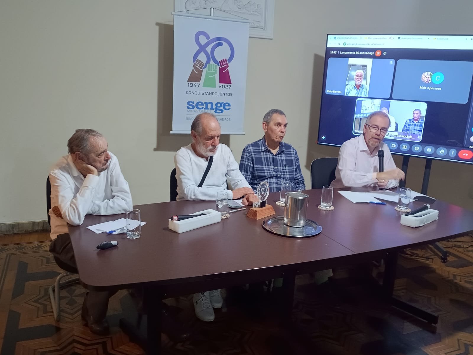 Mesa de abertura do lançamento do Projeto Senge-MG 80 anos, com quatro participantes diante do banner dos 80 anos